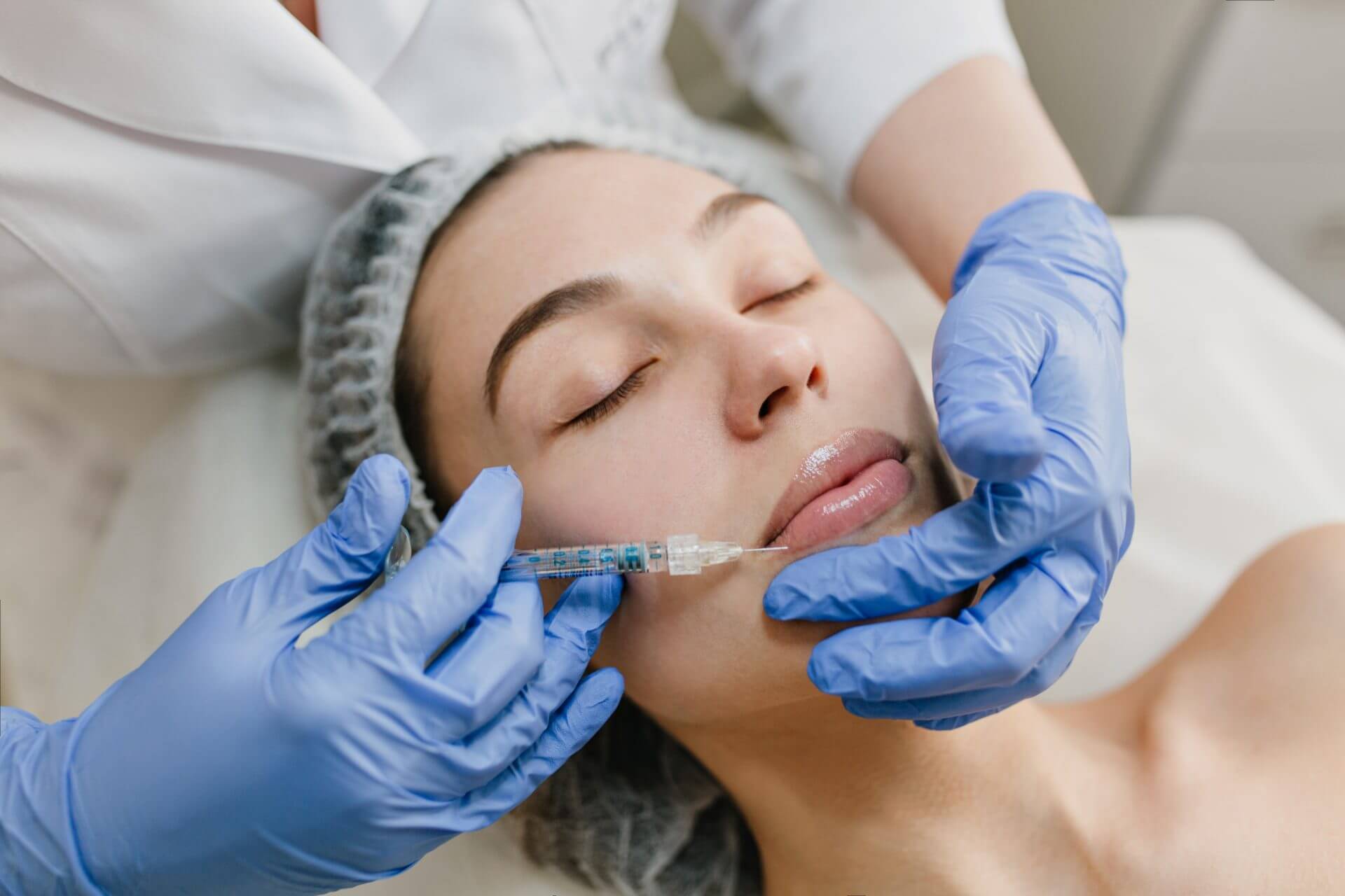 Close up of woman during cosmetology therapy having botox injected into lips by a specialist