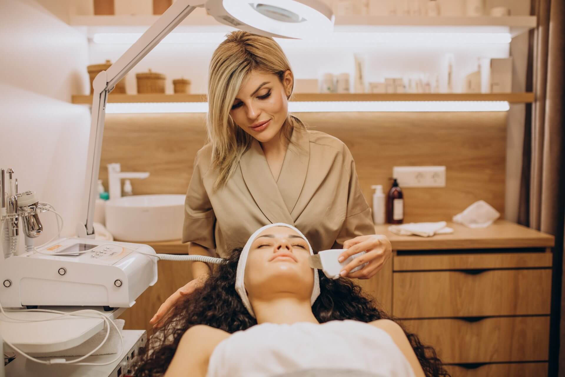 Woman cosmetologist conducting a beauty procedure on young woman