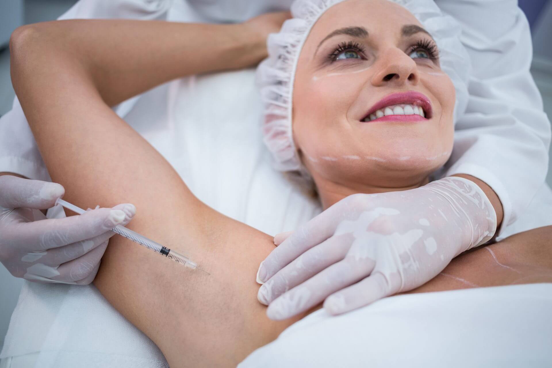 Doctor administering an injection into a smiling woman's armpit.