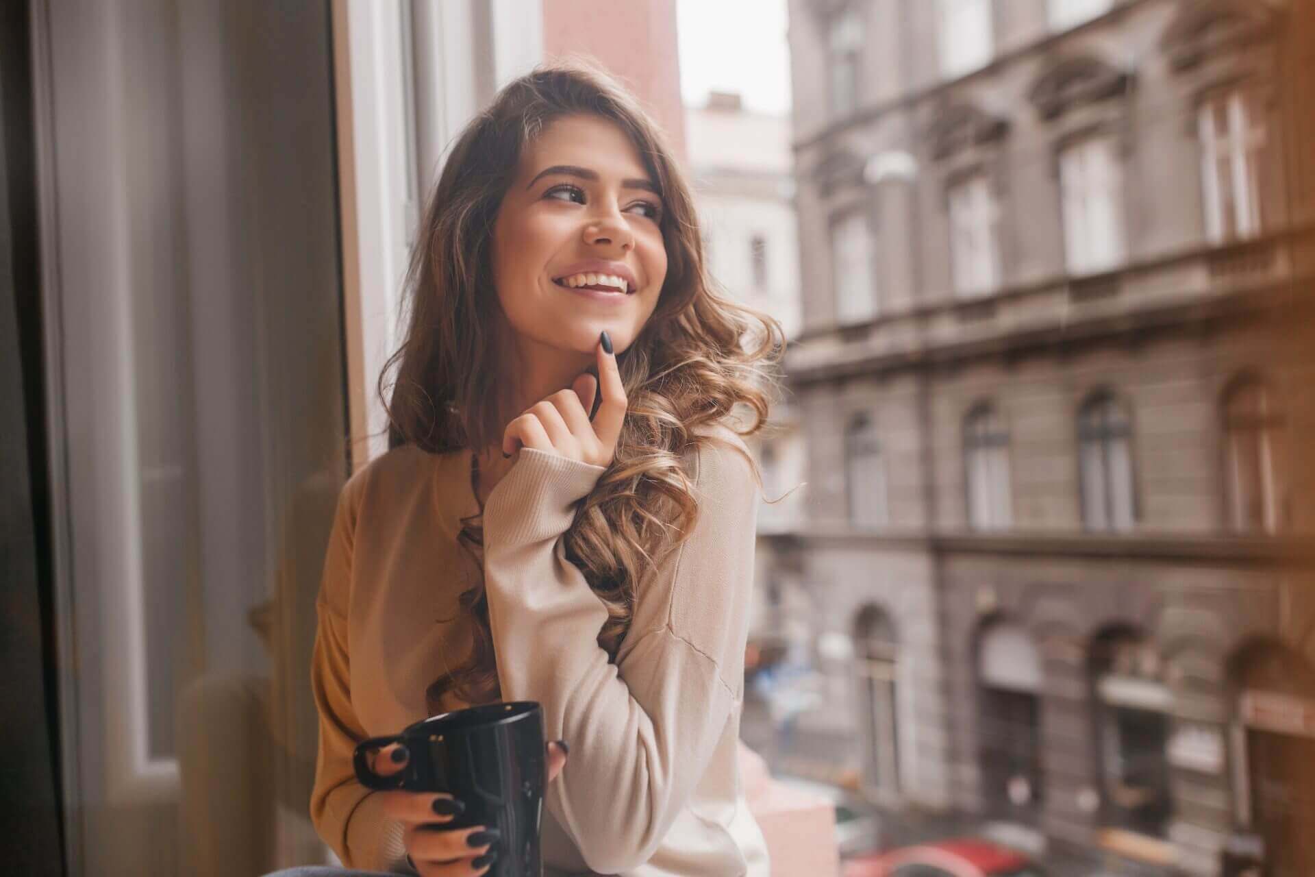 Pretty woman looking out of window at urban landscape