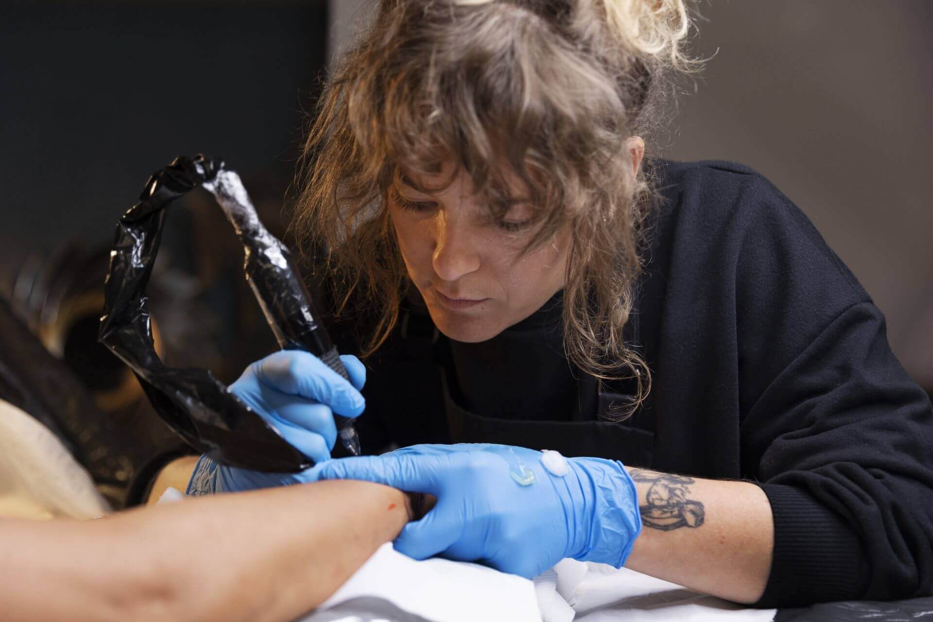 woman focussing on applying tattoo