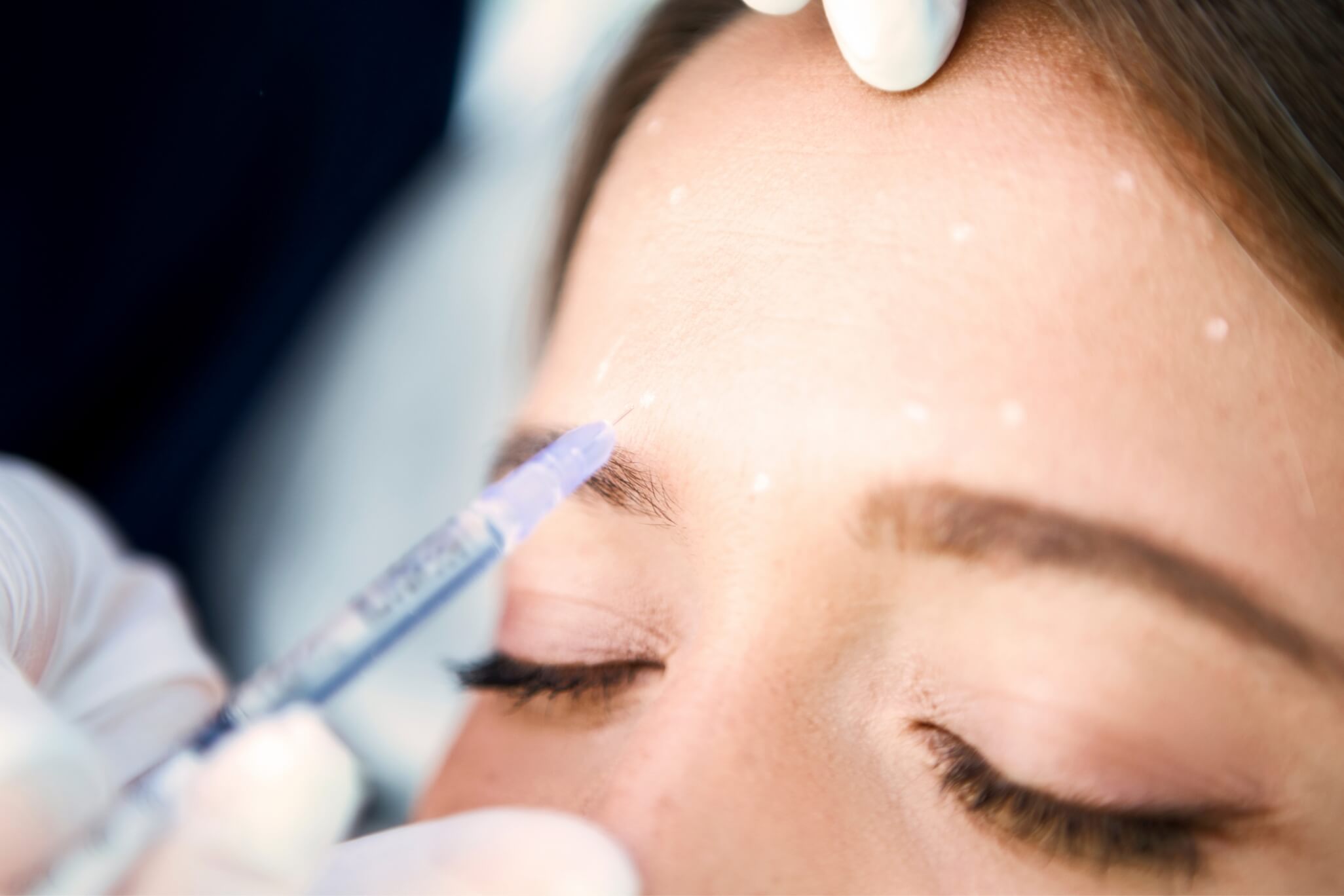 Practitioner using botox injection on woman's face