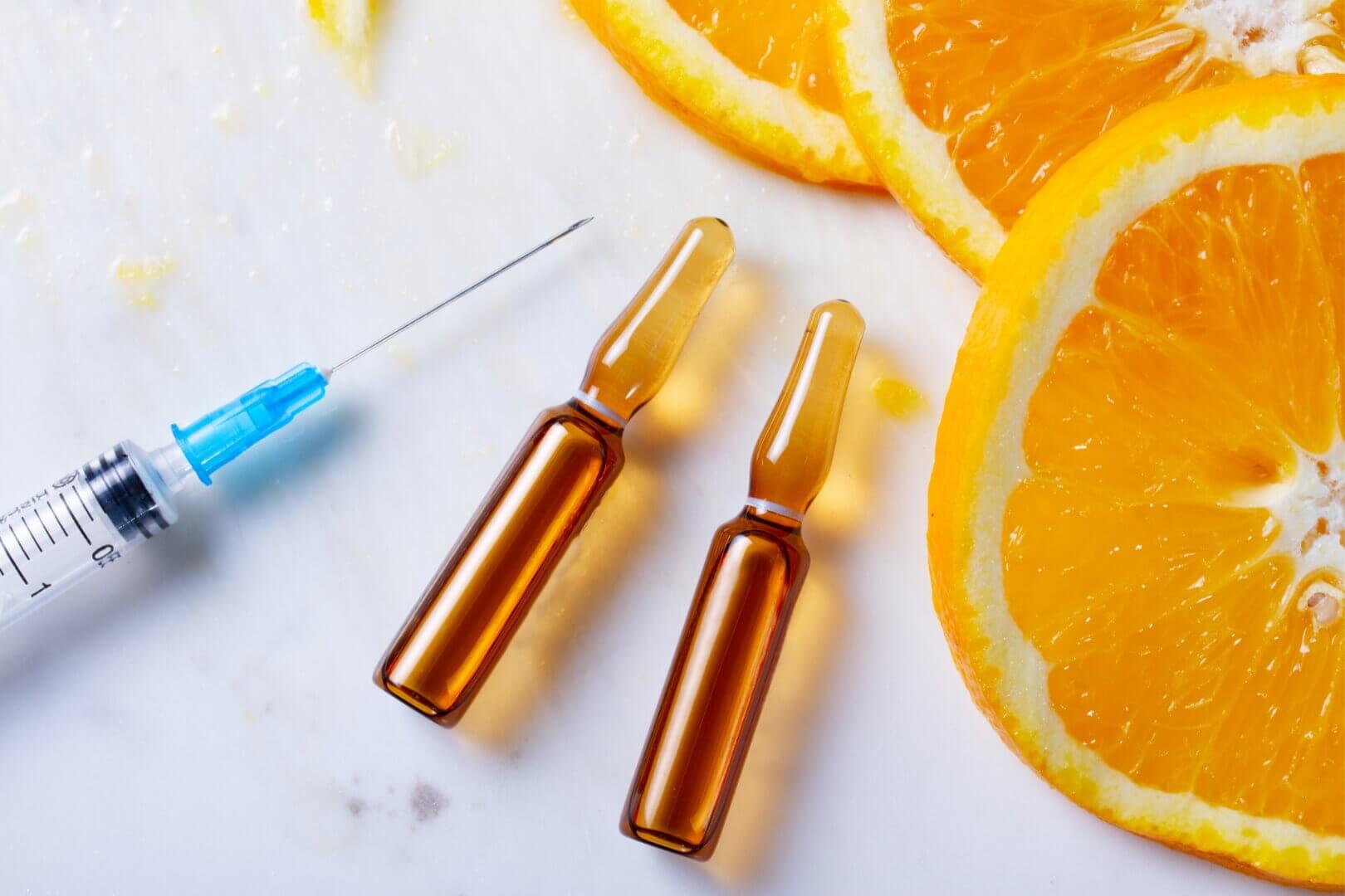 Vitamin C injection with orange slices in background