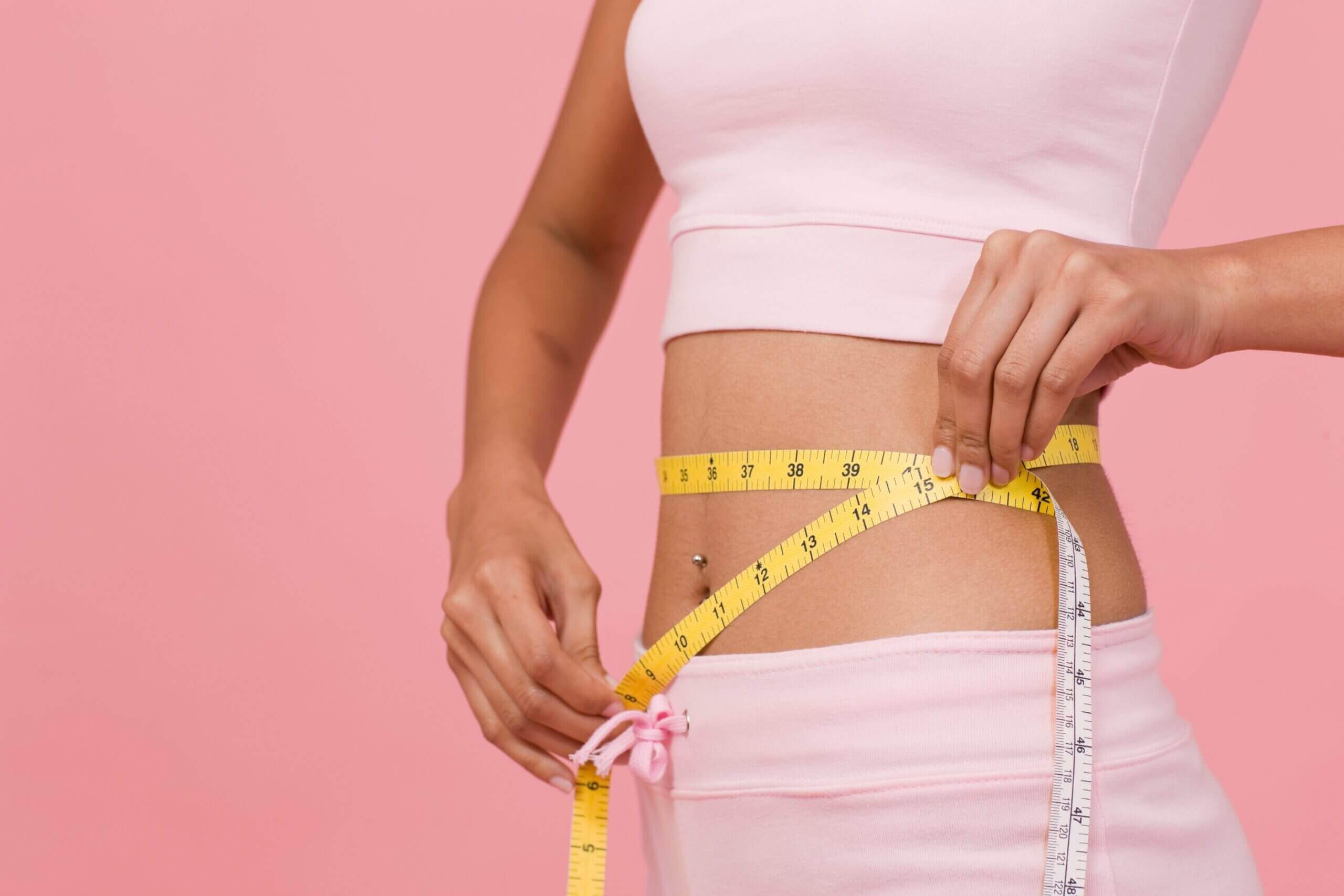 Woman measuring waist following weight loss