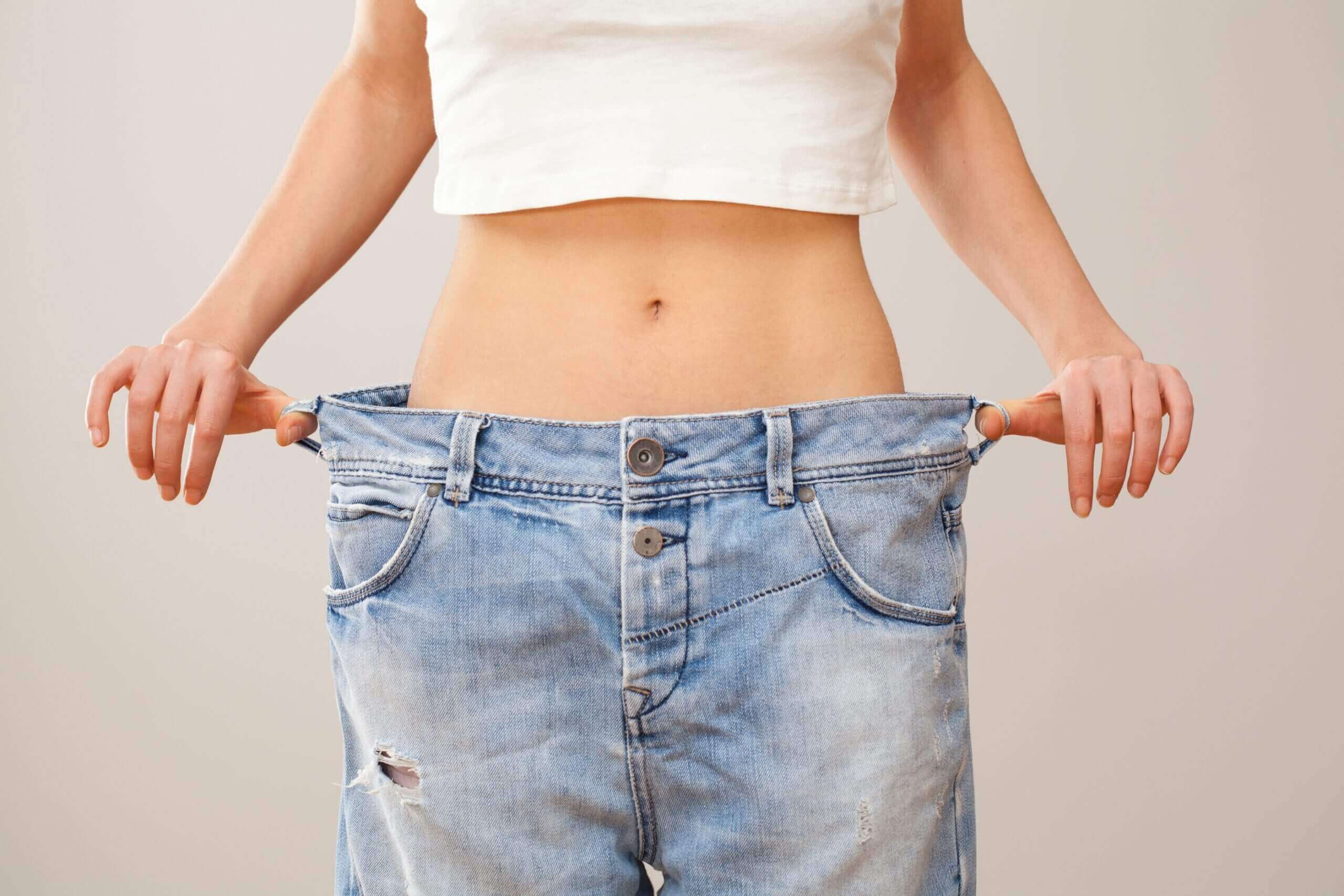 Woman who has lost weight holding jeans that are too big for her