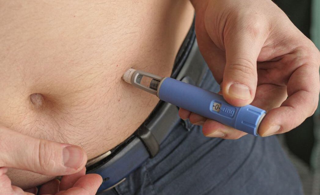 man injecting ozempic into stomach